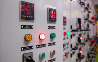 Détail des armoires électriques montrant les voyants et indicateurs numériques après un arrêt d’urgence dans l’usine