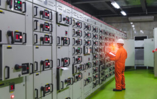 Engineer checking the electrical switchgear, buttons, and selector switches in a low-voltage motor control room