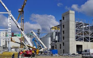 Site industriel en construction avec structures métalliques et engins de chantier