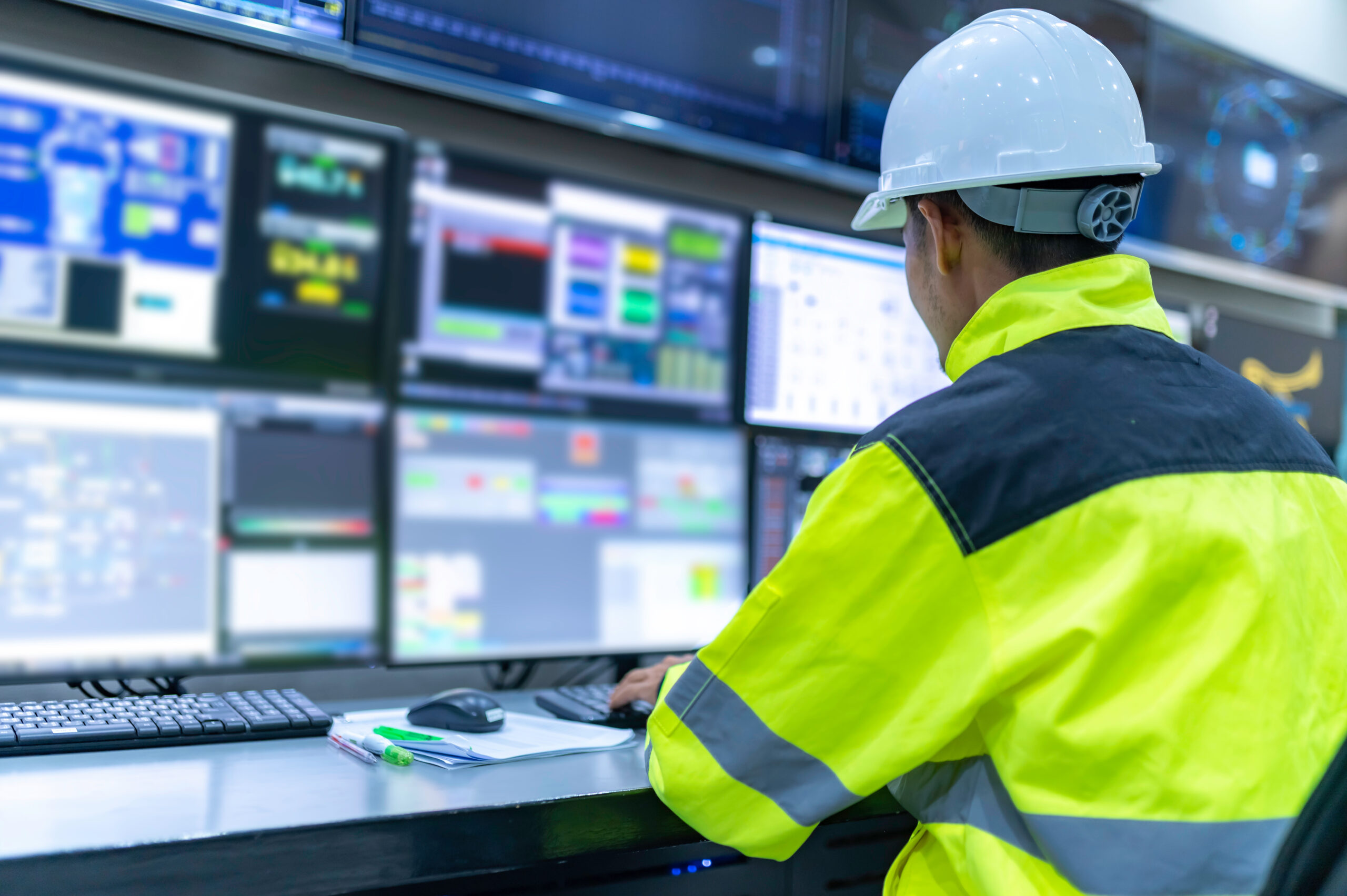 Ingénieur supervisant les programmes et systèmes depuis plusieurs écrans dans la salle de contrôle