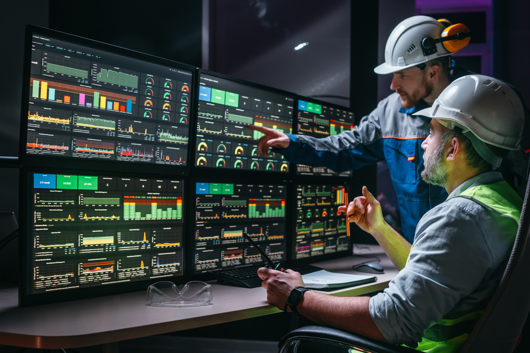 Operators in safety gear reviewing indicators and data in the industrial control room